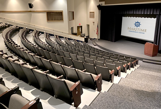 an auditorium with rows of seats and a large screen that says maritime conference center