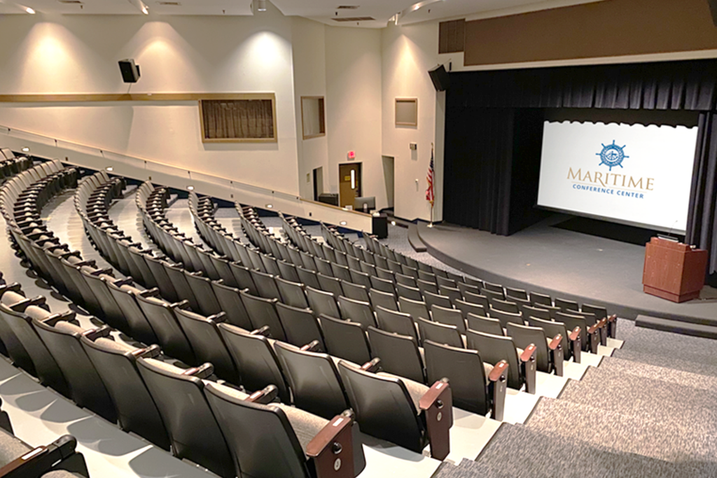 an auditorium with rows of seats and a large screen that says maritime conference center