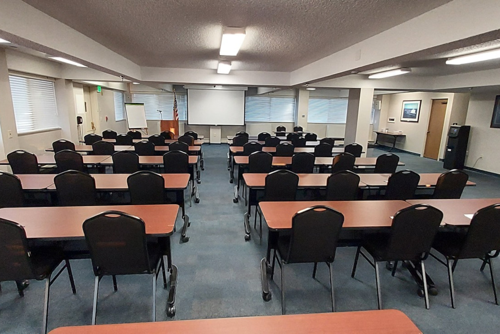 rows of tables and chairs in a room with a projector screen