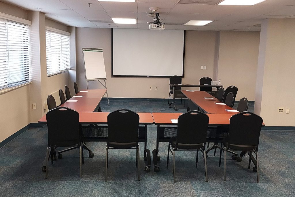 a conference room with tables, chairs, and a projector screen